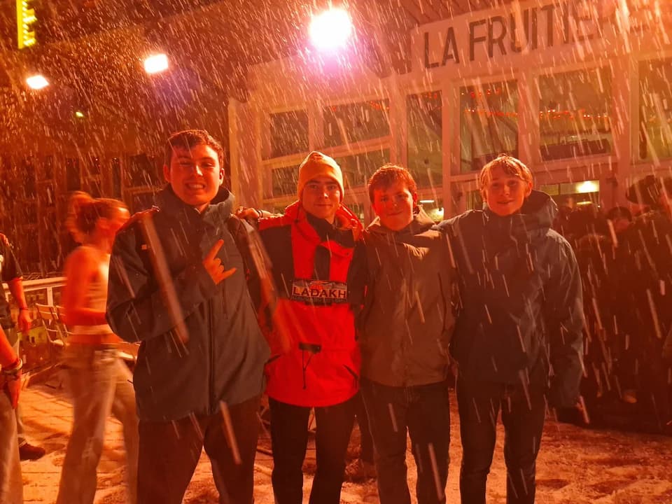 Friends outside a warmly lit restaurant in the snow